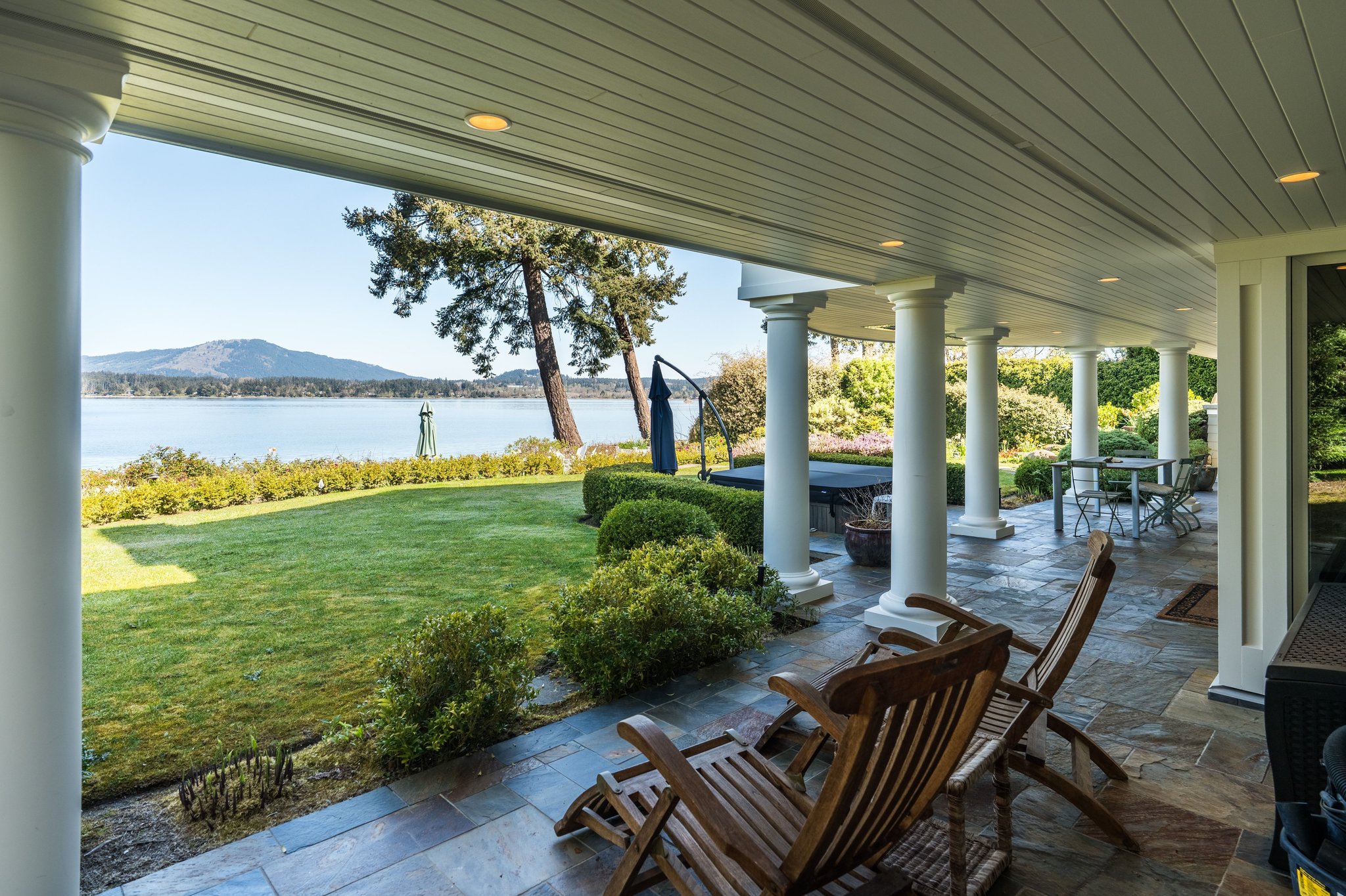 Lower veranda with teak chairs overlooking the garden and Saanich Inlet